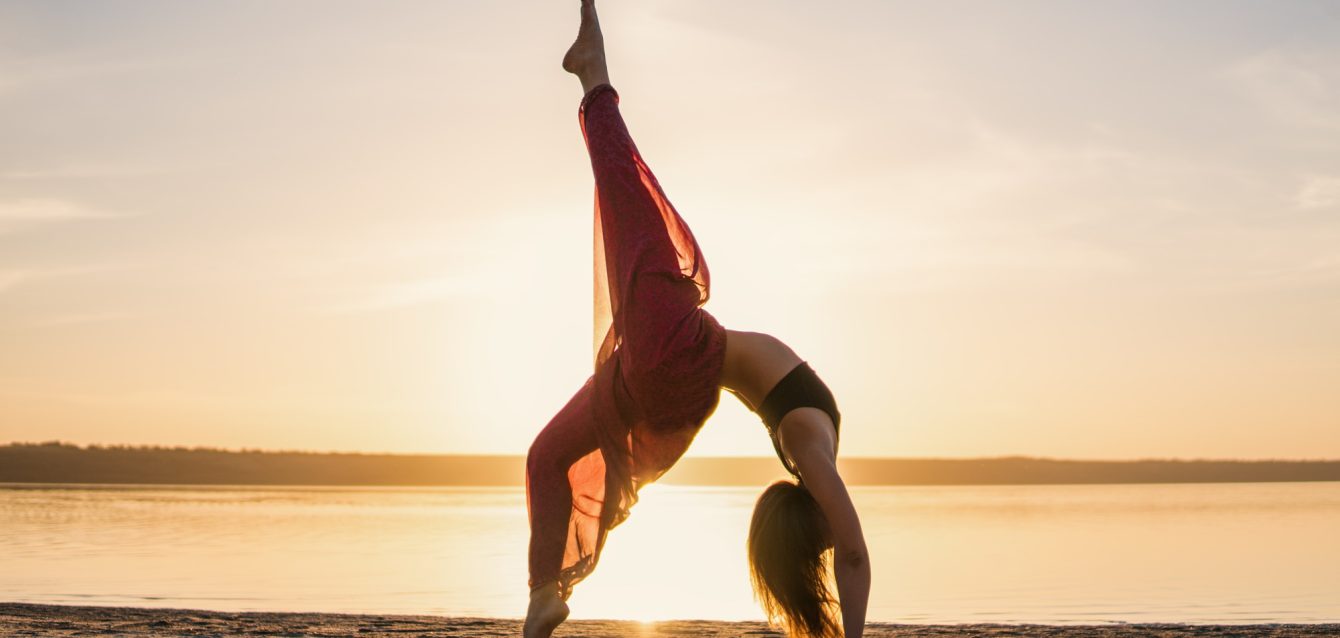 Silhouette yoga woman on the beach at sunset