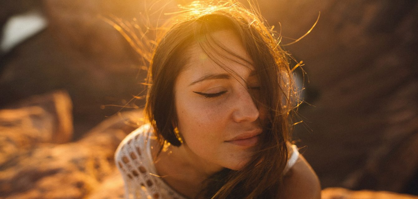 Woman enjoying sunlight with a serene expression.